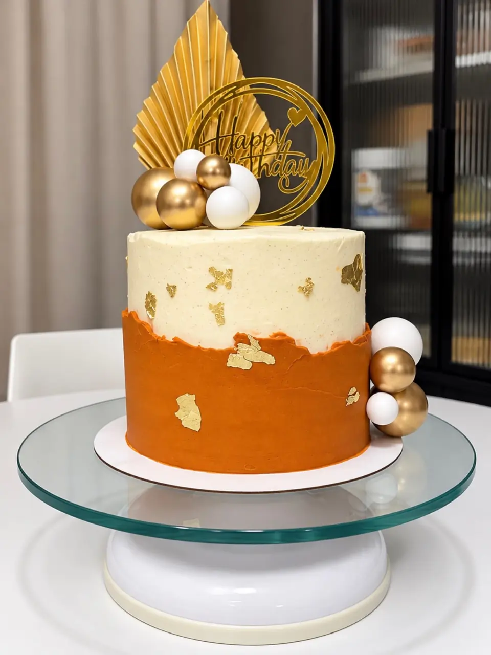 Orange and gold carrot cake with gold sphere and leaf toppers